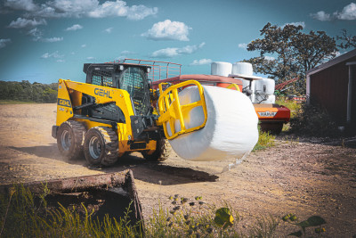 Gehl skid loader carrying hay bale